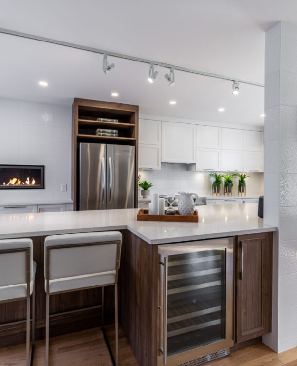 Image de la cuisine rénovée par AMC Design avec un foyer au gaz encastré. Les armoires, les comptoirs, les appareils électroménagers et le foyer au gaz encastré créent un espace fonctionnel et esthétique pour les propriétaires. Les tons neutres et les finitions en bois ajoutent une touche de chaleur à la pièce